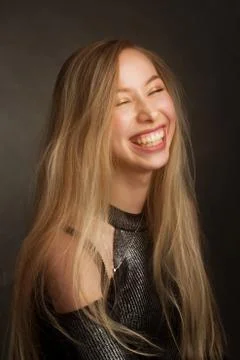 Portrait of a blonde in the Studio on a dark background in a black shiny blou Stock Photos