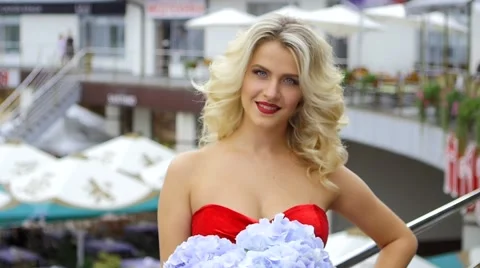 Portrait of blonde woman in a red dress with a bouquet of flowers in their hands Stock Footage