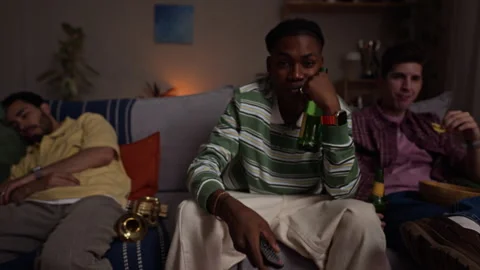 Portrait of Bored Black Man Switching Tv Channels with Remote Control Stock Footage 344650949