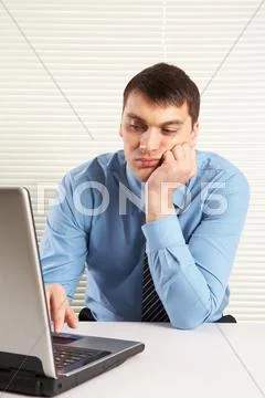Portrait of bored businessman looking at laptop monitor while typing Stock Photos