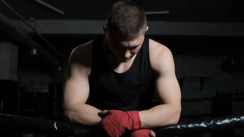 Portrait of a boxer guy in the gym leaning on the ropes and looking at the Stock Footage 110736558