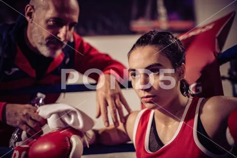 Portrait of boxing coach and female boxer sitting in boxing ring. Stock ...