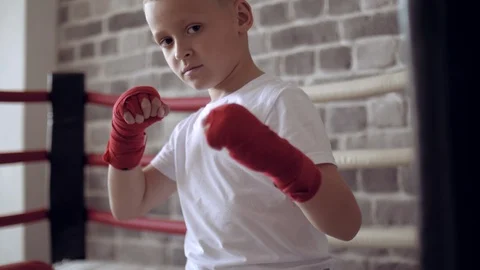 Portrait of boy boxer is wrapped with red bandages, swinging with his hands. Stock Footage 111551322