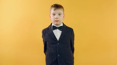 Portrait boy fixing bow tie looking at camera and smiling on yellow background Video stock 126330815