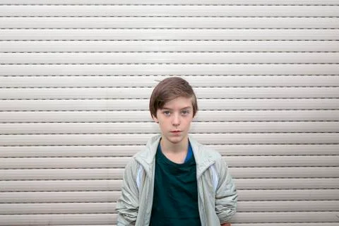 Portrait of a boy with gray roller shutter in background Foto stock