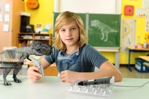 Portrait of boy with hand held computer and 3D model of tyrannosaurus rex Stock Photos