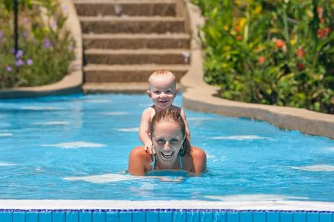 Portrait of boy having fun in pool with joyful mother. Stock Photos