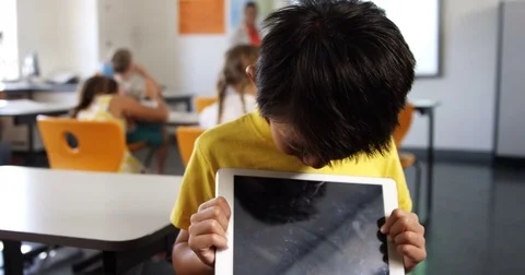 Portrait of boy holding digital tablet in classroom Vídeos de archivo 70548287