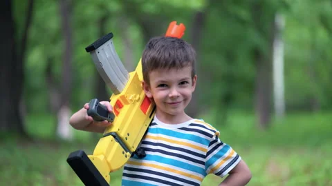 Portrait boy with large toy weapons outdoors Stock Footage 155312464