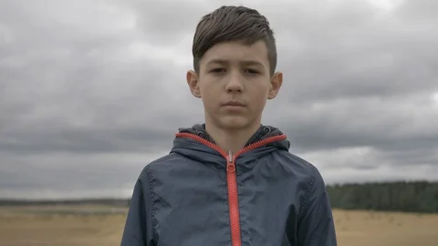 Portrait of a boy looking at the camera outdoors, cloudy weather Video stock 114191623