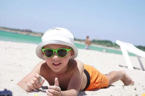 Portrait of a boy lying on a sandy beach on a Sunny summer day, against the Stock Photos