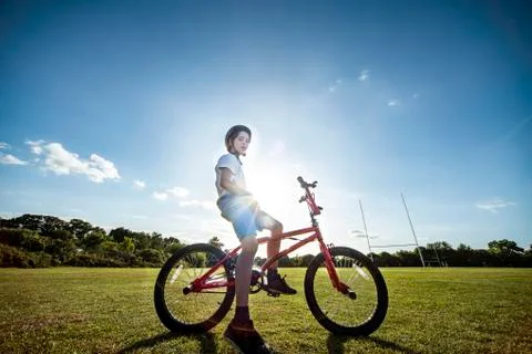 Portrait of boy sitting on his BMX bicycle, wearing cycling helmet. Stock Photos