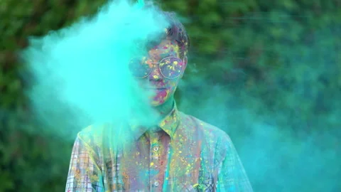 Portrait of boy standing being covered in coloured powder at holi festival Stock Footage 134496043