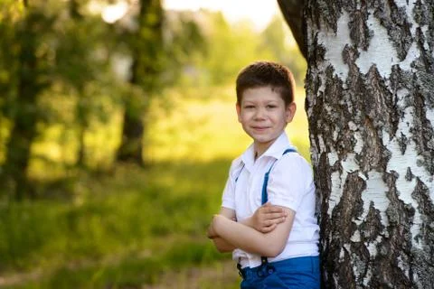 Portrait boy standing near the tree in park,folded his hands in front of him Stock Photos