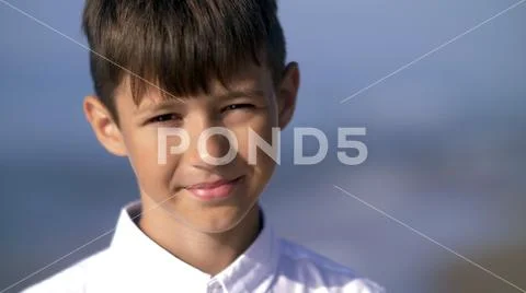 Portrait of a boy who squint from the sun and looks into the camera Stock Photos
