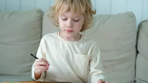 Portrait of a boy whose hand is tired while writing Video stock 296446955
