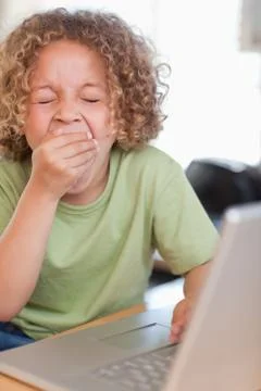 Portrait of a boy yawning while using a laptop Stock Photos