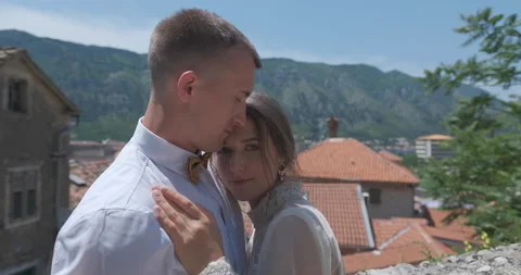 Portrait of the bride looking at camera and groom hugging her in old town Stock Footage 137906408