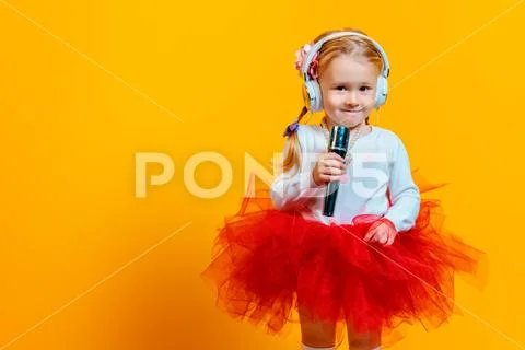 A portrait of a bright young pretty girl in skirt with a microphone. Fashion Stock Photos