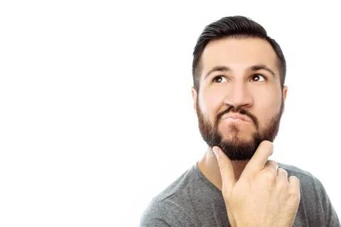 Portrait of brooding bearded man in grey t-shirt looking up and putting hand  Stock Photos