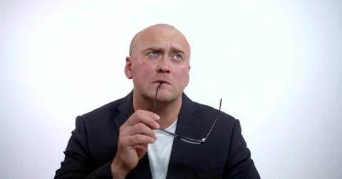 A portrait of a brooding middle-aged bald businessman wearing glasses and a Stock Photos