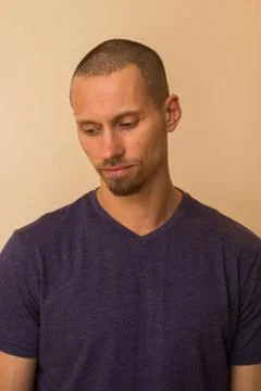 Portrait of a brooding young man in a blue or purple photoball against a beige 写真素材