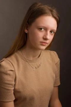 Portrait of a brown-haired model in a light brown t-shirt on a brown backgrou Stock Photos