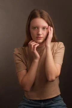 Portrait of a brown-haired model in a light brown t-shirt on a brown backgrou Stock Photos