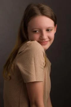 Portrait of a brown-haired model in a light brown t-shirt on a brown backgrou Stock Photos