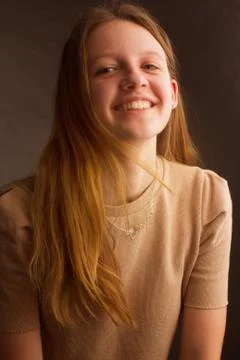Portrait of a brown-haired model in a light brown t-shirt on a brown backgrou Stock Photos