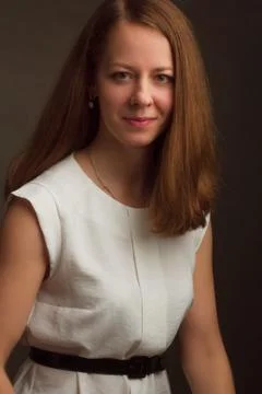 Portrait of brown-haired model in a white dress on a dark background in the S Stock Photos