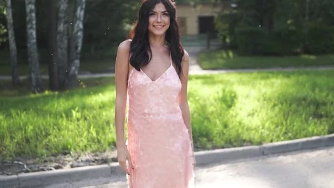 Portrait of brunette in a cocktail dress on a background of green trees. young Stock Footage