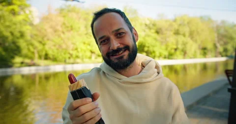 Portrait of a brunette guy with a beard in a White hoodie who poses and holds a Stock Footage 280630210