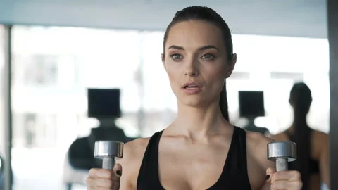 Portrait of brunette with slender physique working out exercises using dumbbells Video stock 199490877