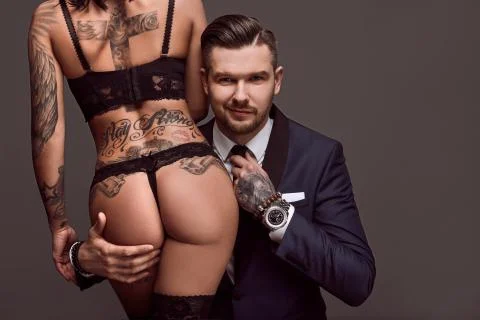 Portrait of a brutal man in suit and sexy girl Stock Photos
