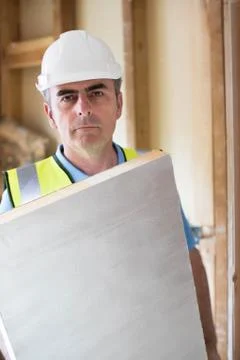 Portrait Of Builder Fitting Insulation Boards Into Roof Of New Home Stock Photos