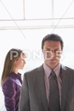 Portrait of business man, female colleague in background Stock Photos