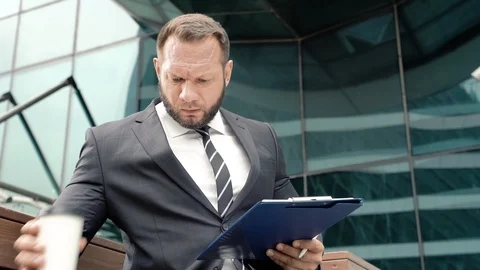 Portrait of a business man taking notes on paper and drinking coffee Stock Footage 111759618