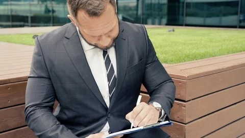 Portrait of a business man taking notes on paper outdoors Stock Footage 112335480