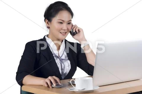 Portrait of business woman speaking on mobile phone while using laptop in off Stock Photos