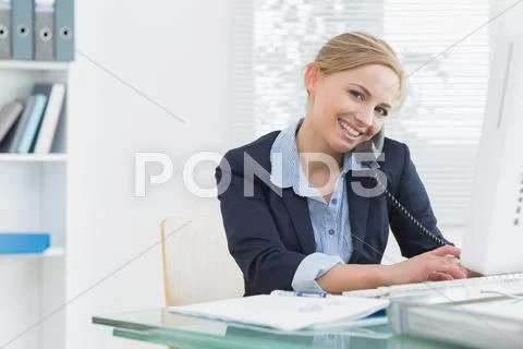 Portrait of business woman using phone and computer at desk Stock Photos