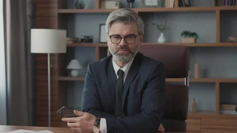 Portrait of businessman with glasses using his smartphone sitting at table Vídeos de archivo 220190917