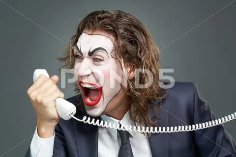 Portrait of businessman with painted face shouting at telephone receiver Stock Photos