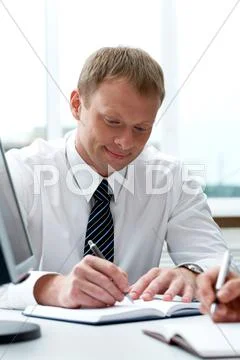 Portrait of businessman writing in notepad during work planning in office Stock Photos