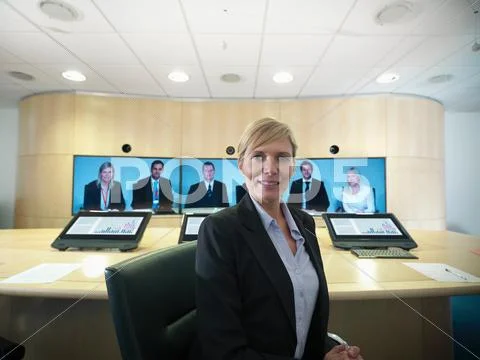 Portrait Of Businesswoman Sitting In Meeting Room With Colleagues On Video