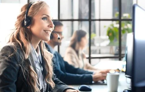 Portrait of call center worker accompanied by her team. Smiling customer support Stock Photos