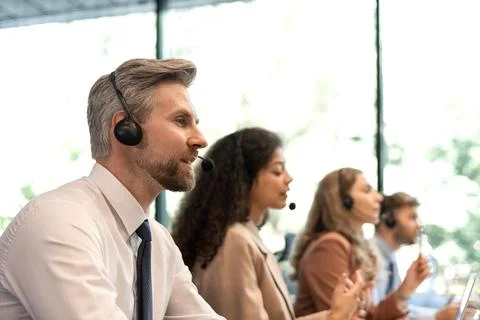 Portrait of call center worker accompanied by his team. Smiling customer supp Stock Photos