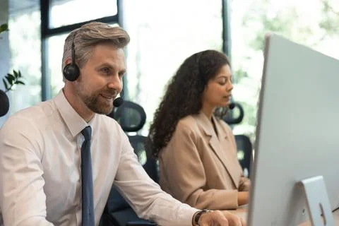 Portrait of call center worker accompanied by his team. Smiling customer supp Stock Photos