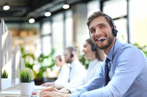 Portrait of call center worker accompanied by his team. Smiling customer supp Stock Photos