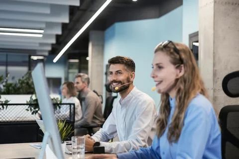 Portrait of call center worker accompanied by his team. Smiling customer su.. Stock Photos
